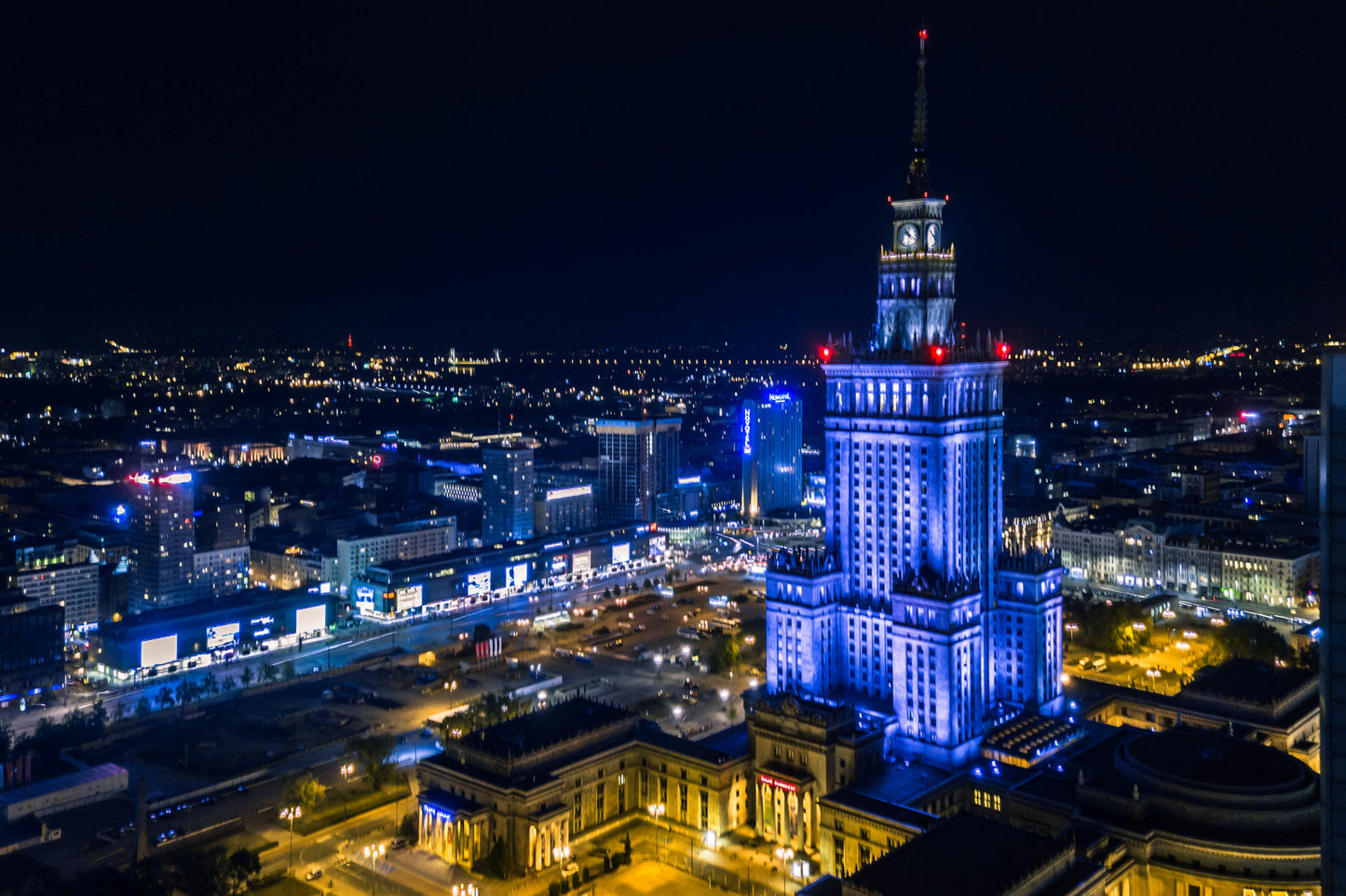 Obraz Na Płótnie Oświetlona Warszawa Nocą – świetlisty pejzaż miejski do wnętrz nowoczesnych i industrialnych 120x80