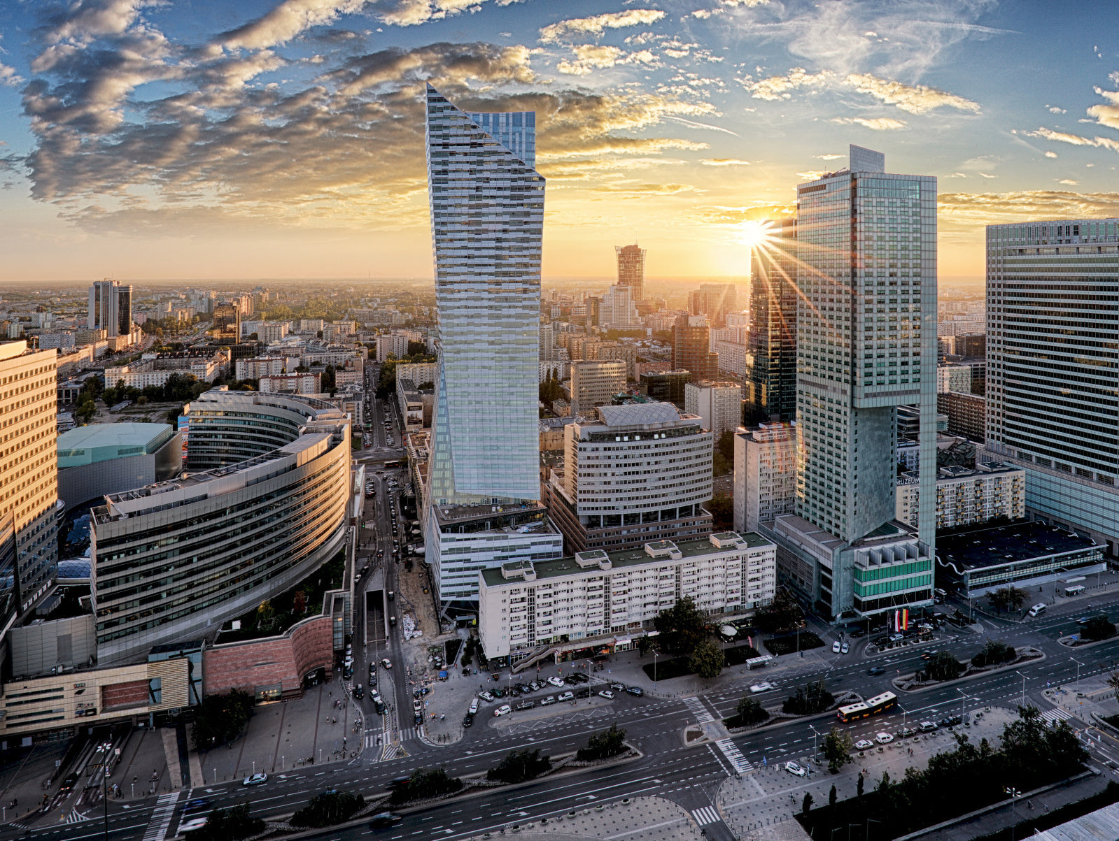 Obraz Wieloczęściowy Warszawskie Wieżowce – miejska panorama o zachodzie słońca do wnętrz nowoczesnych i industrialnych 200x150